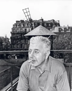 Jacques Prévert sur la terrasse de la Cité Véron. Au fond, les ailes du Moulin Rouge.
