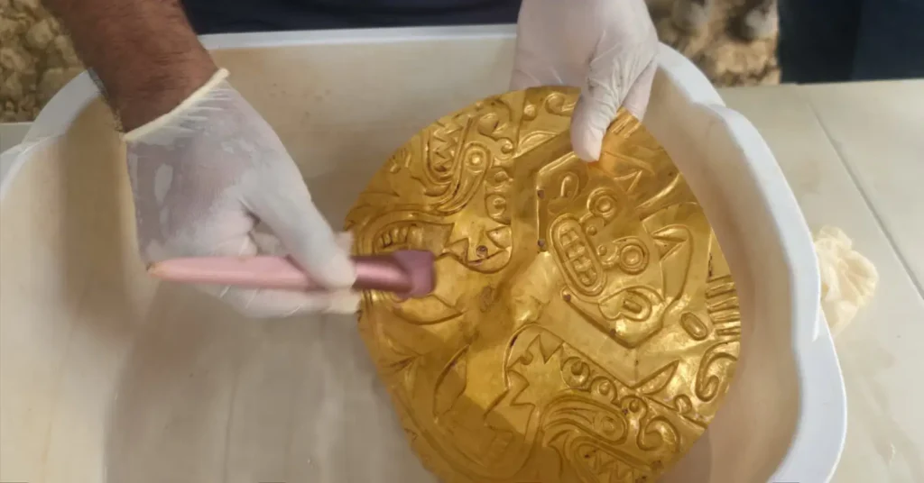 Une tombe vieille de plus de mille ans et dotée d’un riche mobilier funéraire a été mise au jour en février dernier au Panama : nettoyage d'un ornement en or.